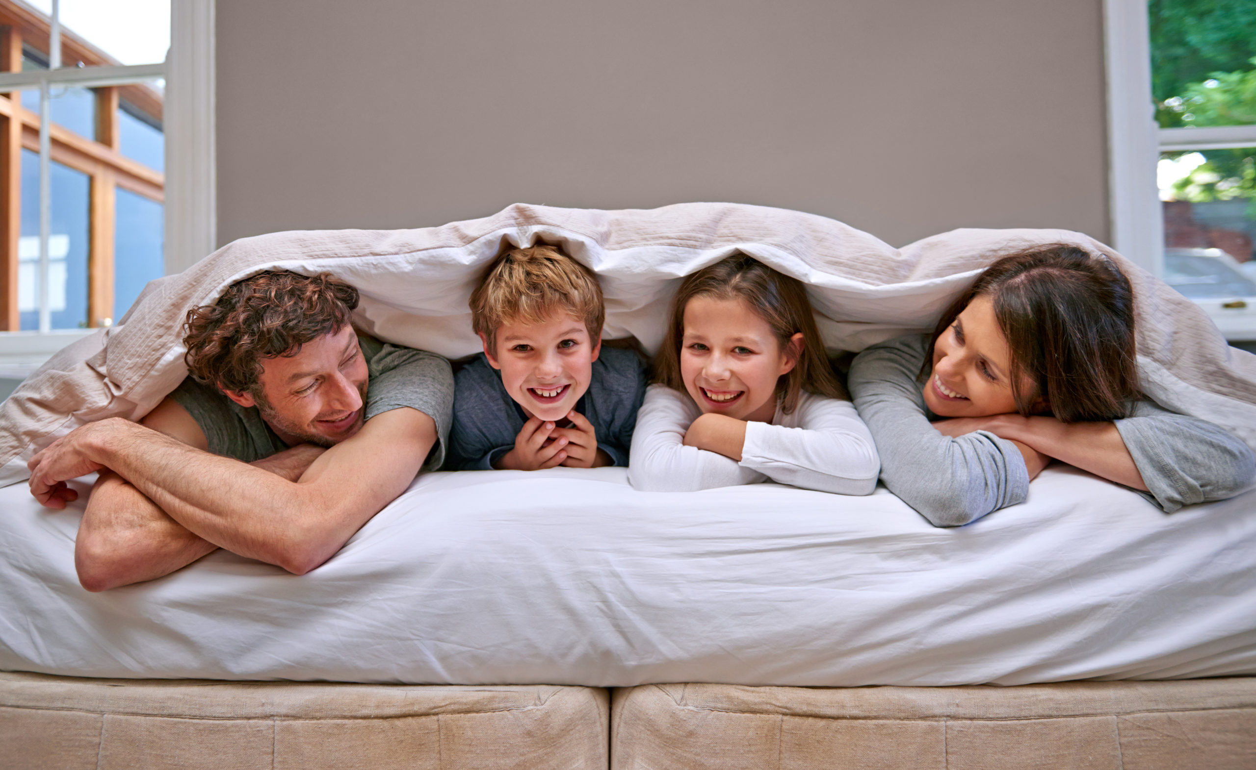 une famille avec parents et enfants joyeux et bien reposé dans un grand lit